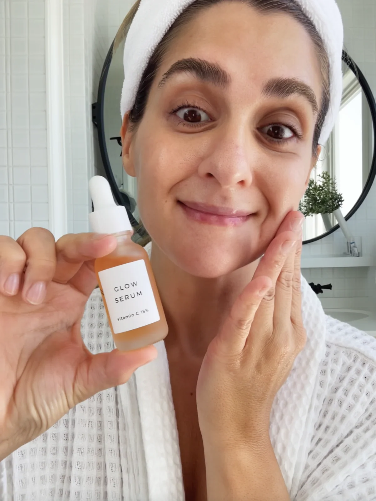 MOSS Image UGC selfie of a woman holding a bottle labelled GLOW SERUM