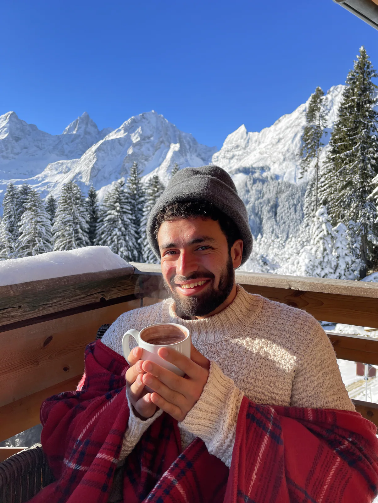 MOSS Image vacation photo of a man with hot chocolate on a snowy Alps balcony