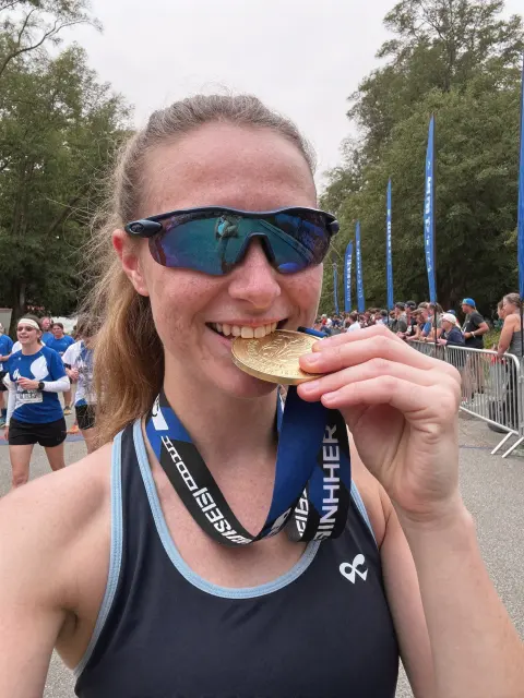 AI photo of a woman with light brown hair: biting a finisher medal, made with KREA 2