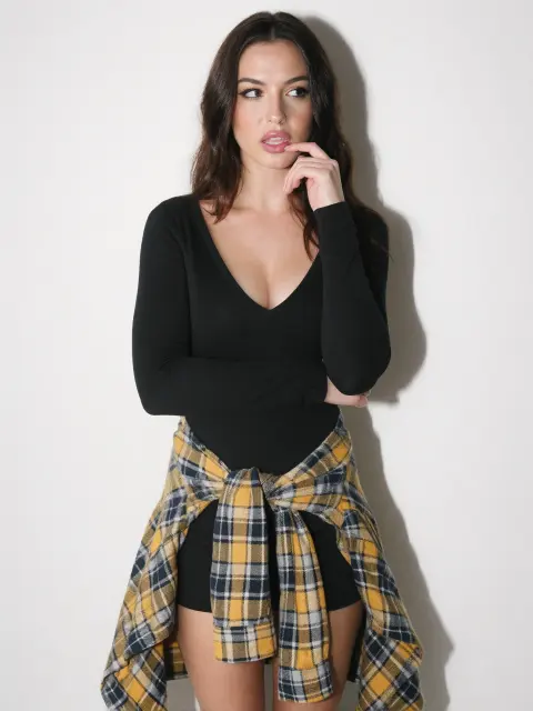 AI photo of a woman with long dark brown wavy hair: black bodysuit with a plaid shirt tied at the waist, made with KREA 2