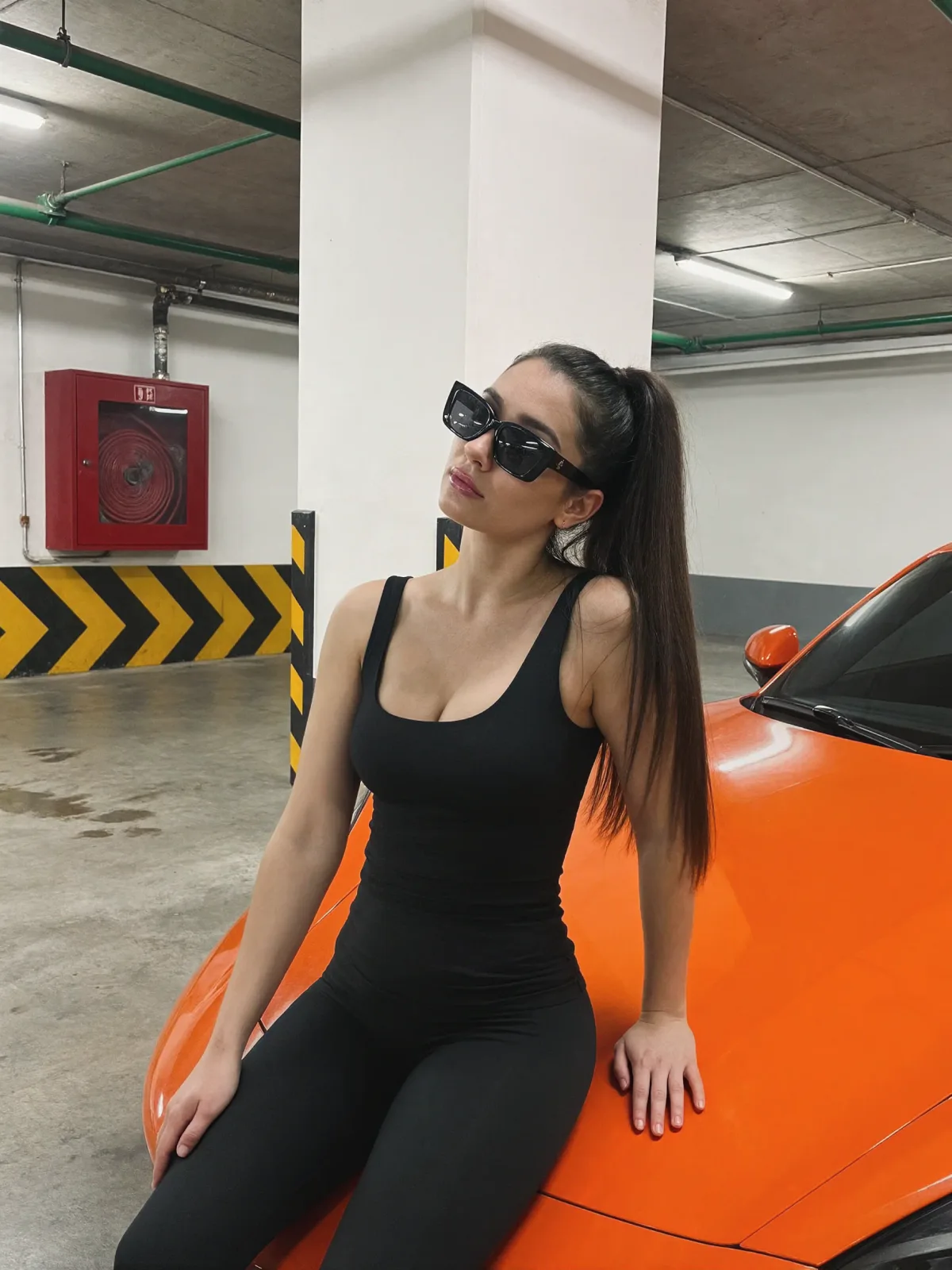 AI photo of a woman with long straight dark brown hair: black jumpsuit on an orange sports car, made with KREA 2