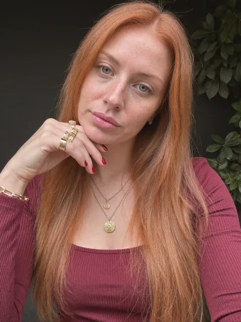 AI photo of a woman with long straight copper-red hair: burgundy top and gold necklace portrait, made with KREA 2