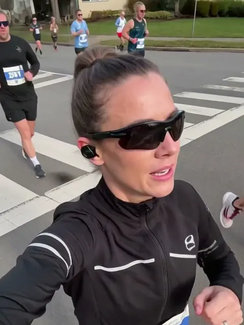 Frame from an AI video of a woman with light brown hair: marathon running selfie video, made with MiniMax H3