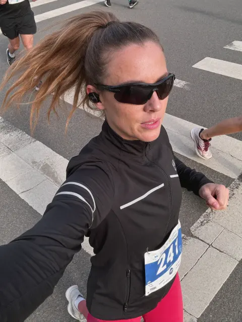 AI photo of a woman with light brown hair: marathon selfie in a running jacket, made with KREA 2