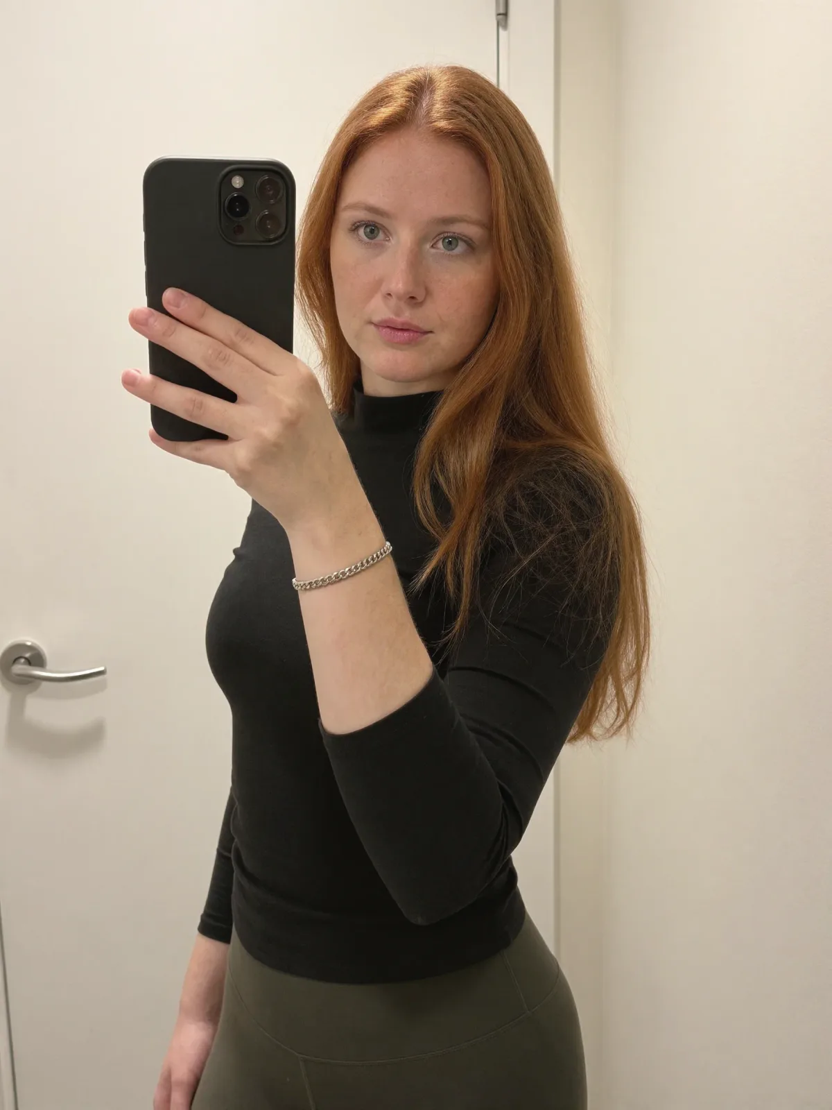 AI photo of a woman with wavy copper-red hair: mirror selfie in a black fitted top, made with KREA 2