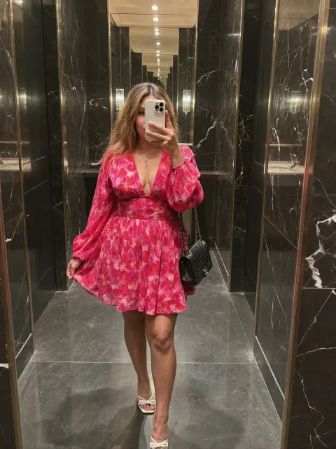 AI photo of a woman with long wavy light brown hair: pink floral dress elevator selfie, made with KREA 2