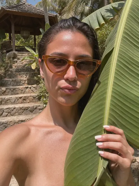 AI photo of a woman with dark hair: tropical leaf portrait in tortoiseshell sunglasses, made with KREA 2
