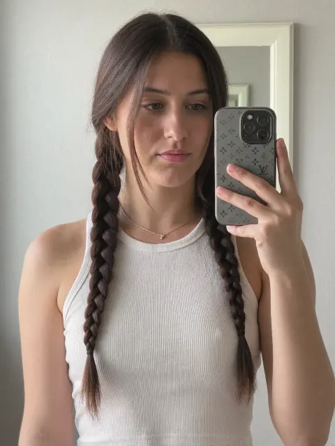 AI photo of a woman with long dark brown hair: white tank and braids bathroom mirror selfie, made with KREA 2