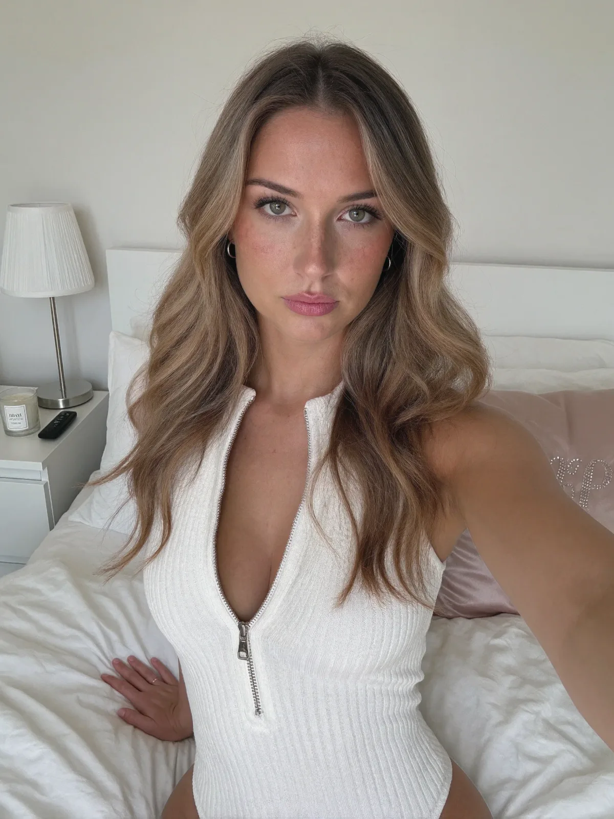 AI photo of a woman with long wavy honey-blonde hair: white zip knit top bedroom portrait, made with KREA 2